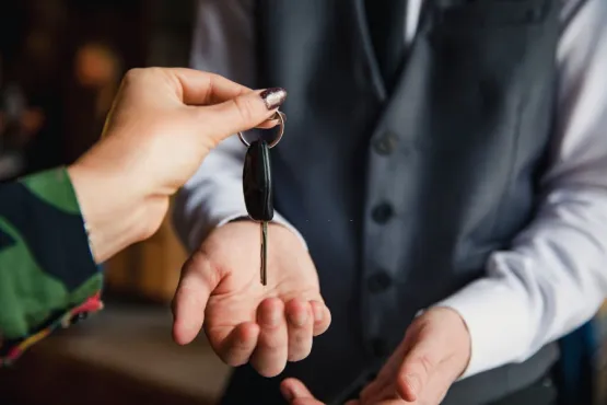 Customer handing car keys to meet and greet valet attendant